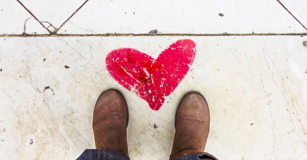 Sidewalk with a red chalk heart and a pair of feet.